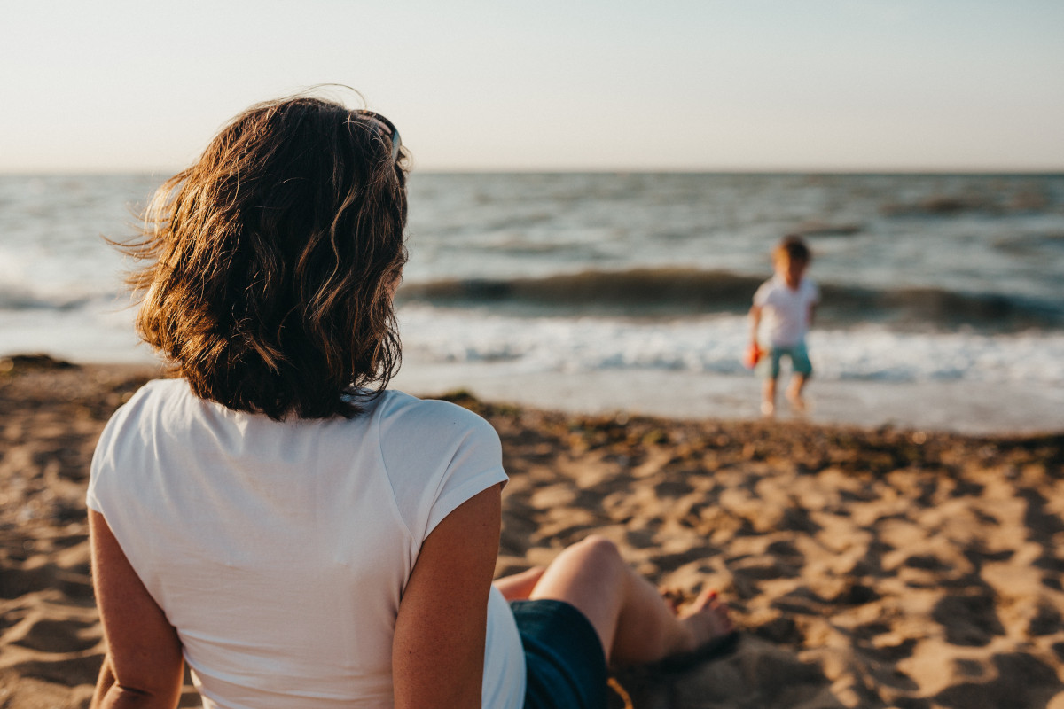 mujer mirando a su hijo en la playa